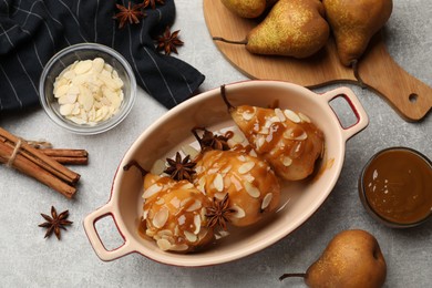 Delicious pears with caramel sauce, almond flakes and spices on grey table, top view