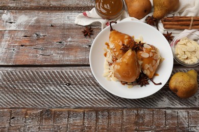 Photo of Delicious pears with caramel sauce, almond flakes and spices on wooden table, top view. Space for text