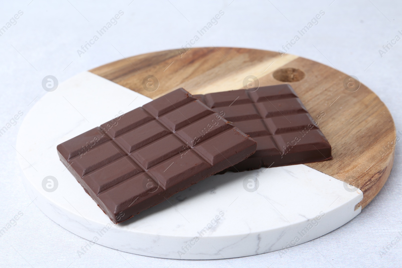 Photo of Pieces of delicious dark chocolate bar on light table, closeup