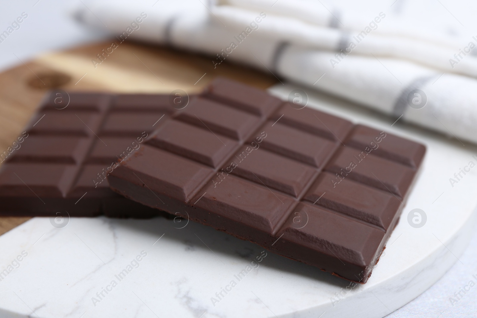 Photo of Pieces of delicious dark chocolate bar on light table, closeup