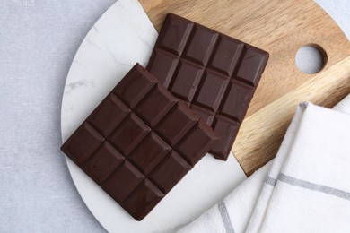 Photo of Pieces of delicious dark chocolate bar on light table, top view