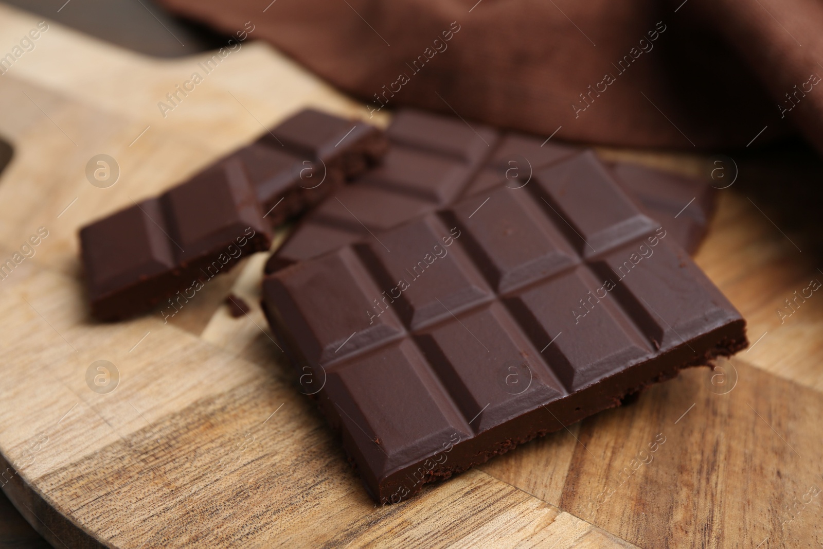 Photo of Pieces of delicious dark chocolate bar on table, closeup