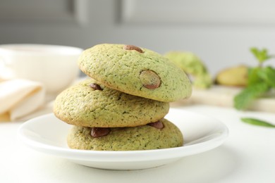 Photo of Delicious mint chocolate chip cookies on white table, closeup