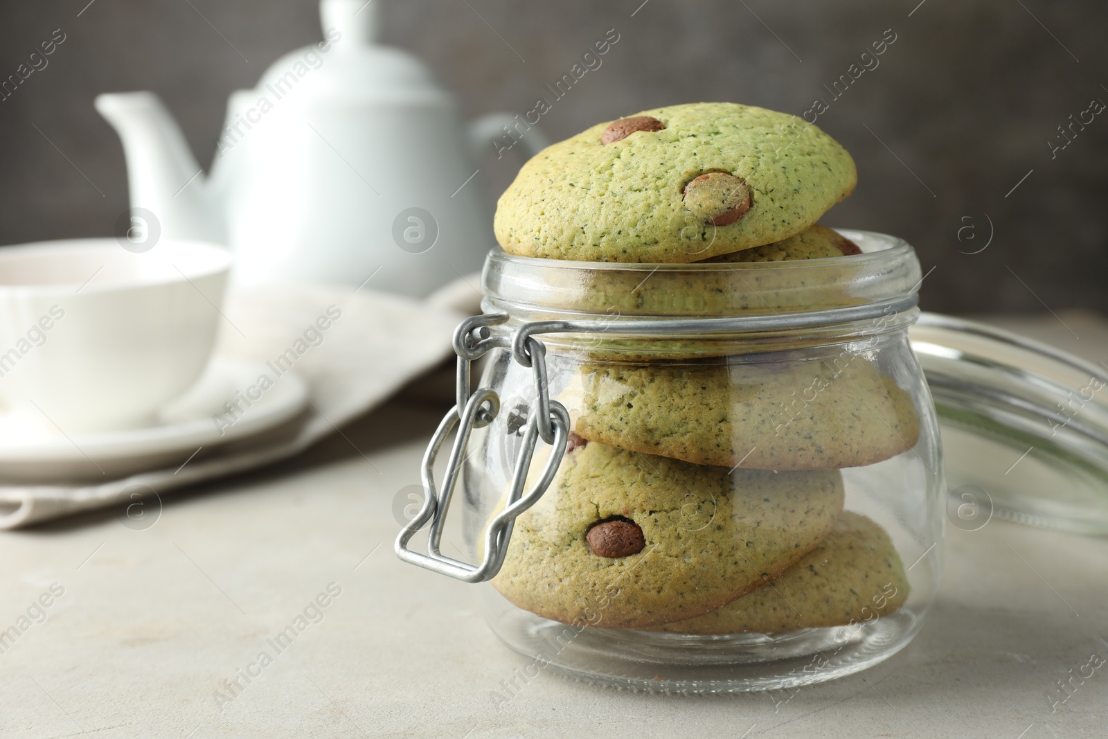 Photo of Delicious mint chocolate chip cookies in jar on light table, closeup