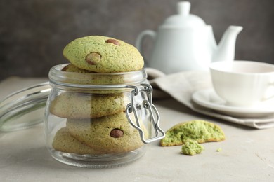 Photo of Delicious mint chocolate chip cookies in jar on light table, closeup