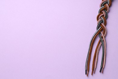 Photo of Braided colorful ropes on lilac background, top view with space for text. Unity concept