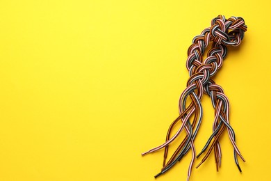 Photo of Braided colorful ropes on yellow background, top view with space for text. Unity concept