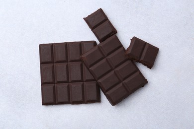 Photo of Pieces of delicious dark chocolate on light table, top view