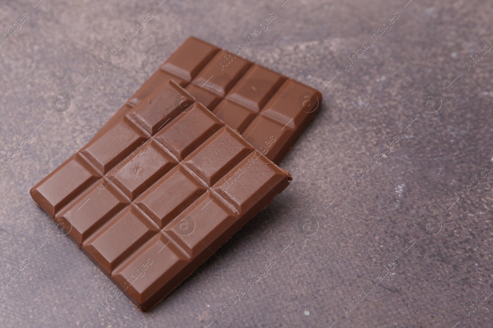 Photo of Pieces of delicious milk chocolate on brown table, closeup. Space for text