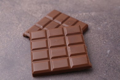 Photo of Pieces of delicious milk chocolate on brown table, closeup