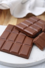 Photo of Pieces of delicious milk chocolate on white table, closeup