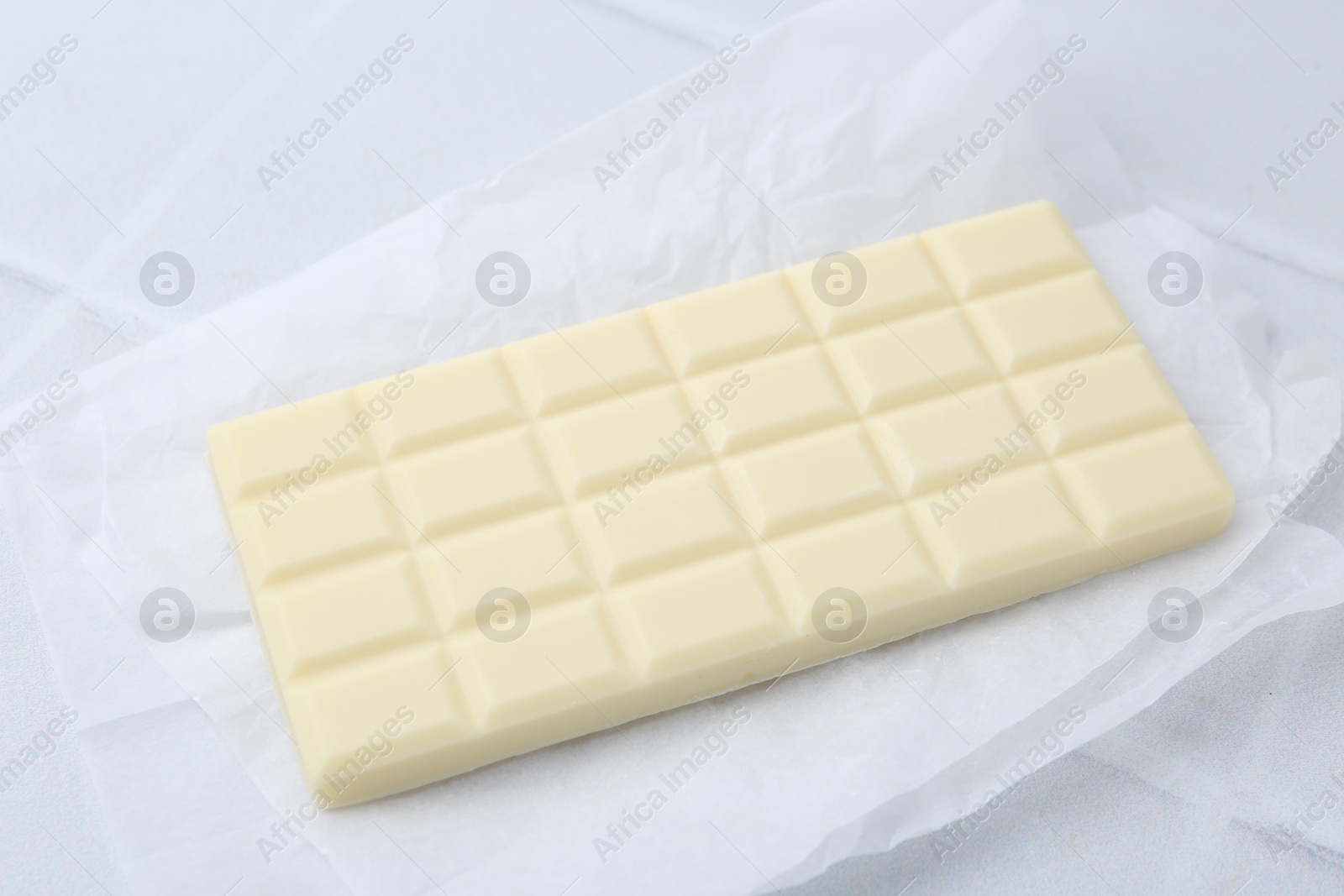 Photo of Delicious white chocolate bar on tiled table