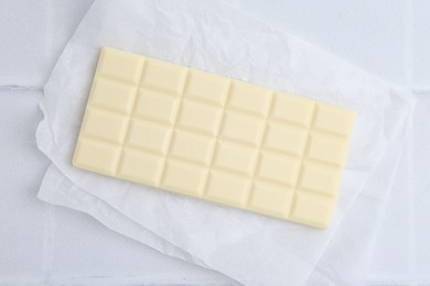 Photo of Delicious white chocolate bar on tiled table, top view