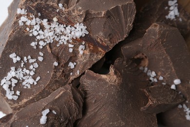 Photo of Pieces of tasty chocolate with salt on table, closeup