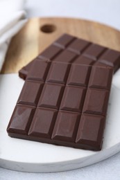 Photo of Pieces of delicious dark chocolate bar on light table, closeup