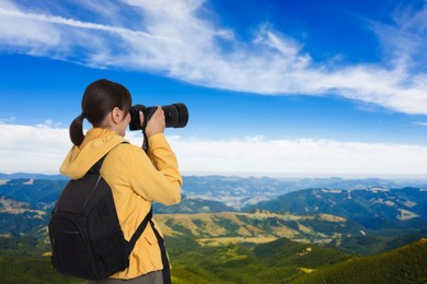 Image of Woman with backpack taking photo in mountains