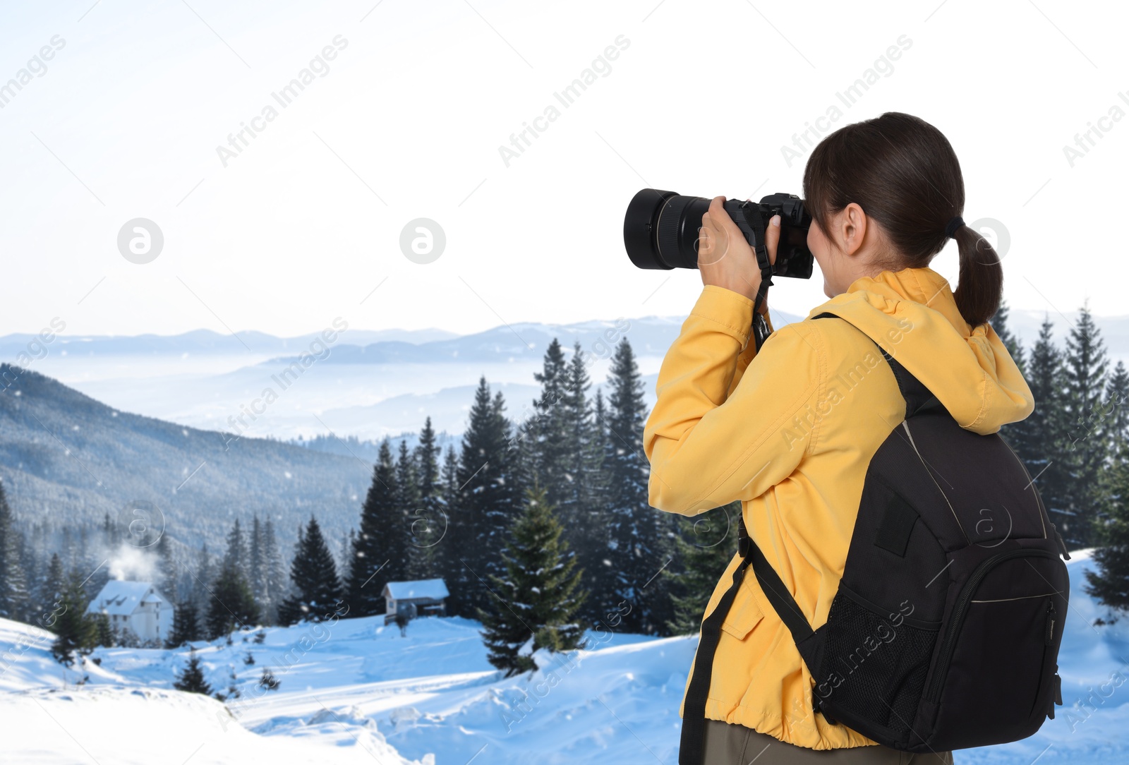 Image of Woman with backpack taking photo in mountains