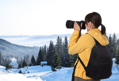 Image of Woman with backpack taking photo in mountains