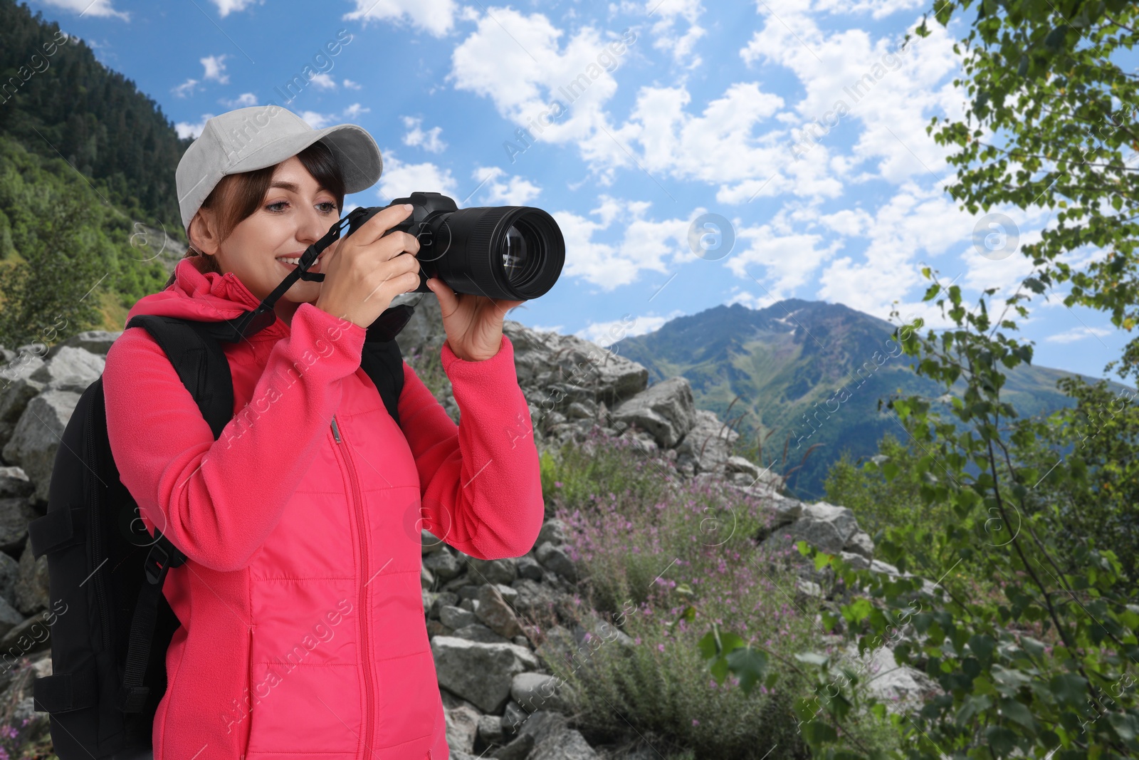 Image of Woman with backpack taking photo in mountains