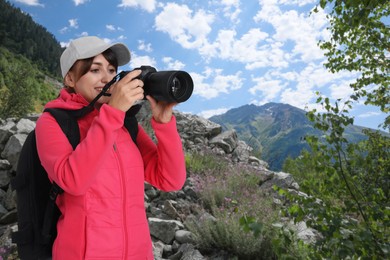 Image of Woman with backpack taking photo in mountains