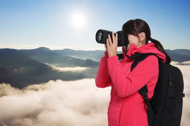 Image of Woman with backpack taking photo in mountains