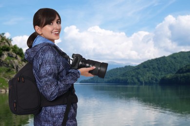 Image of Photographer with backpack and camera near river in mountains