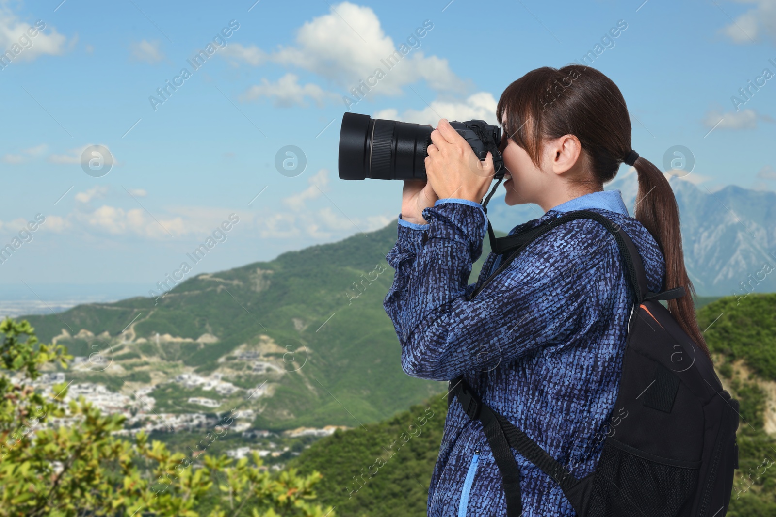 Image of Woman with backpack taking photo in mountains