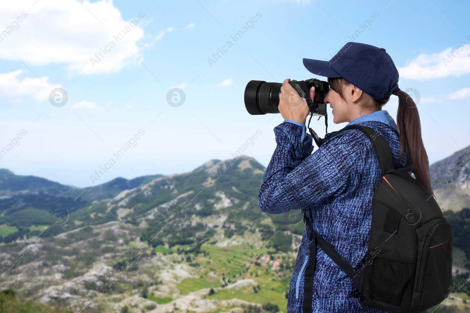 Image of Woman with backpack taking photo in mountains