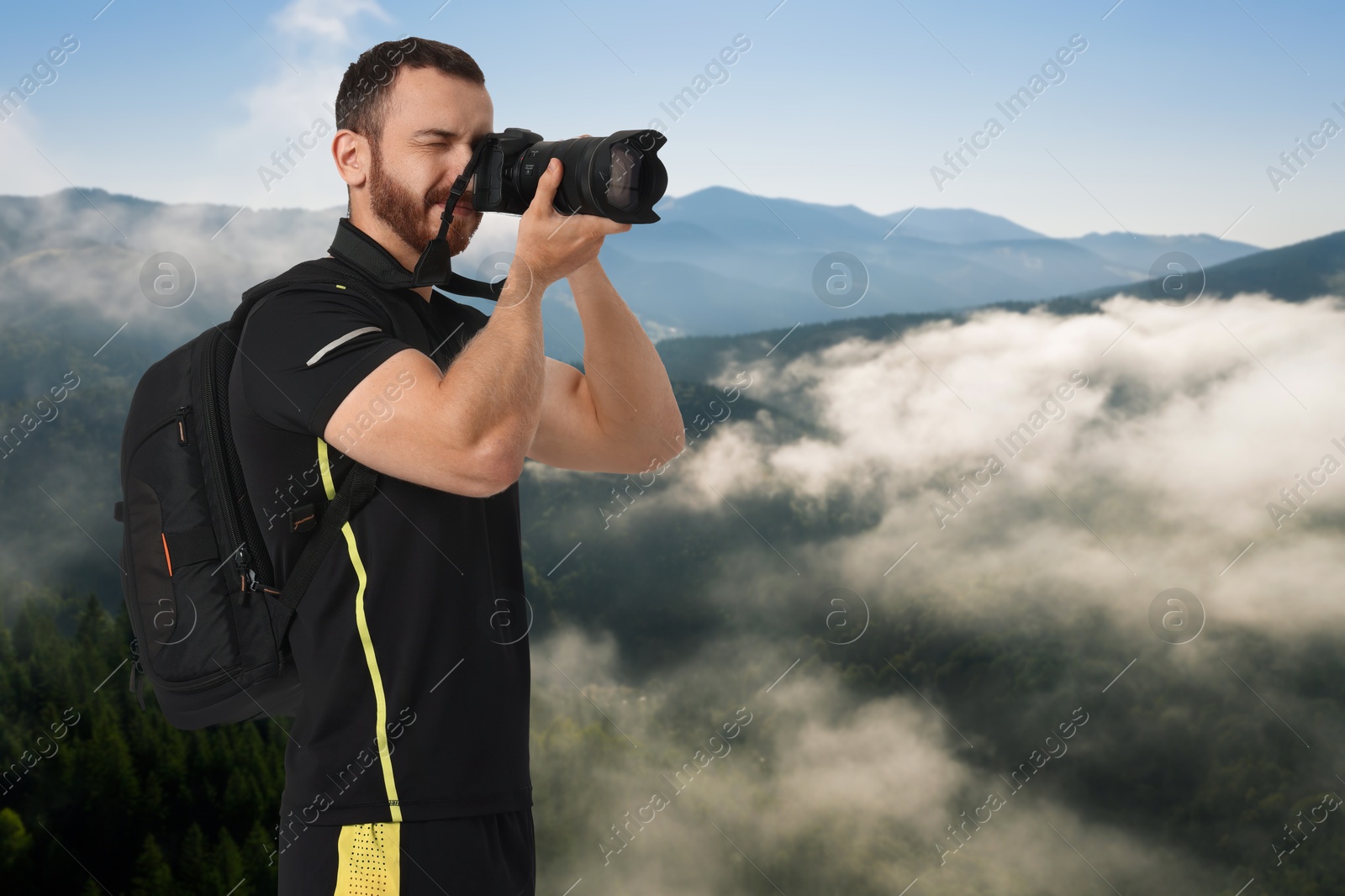 Image of Man with backpack taking photo in mountains