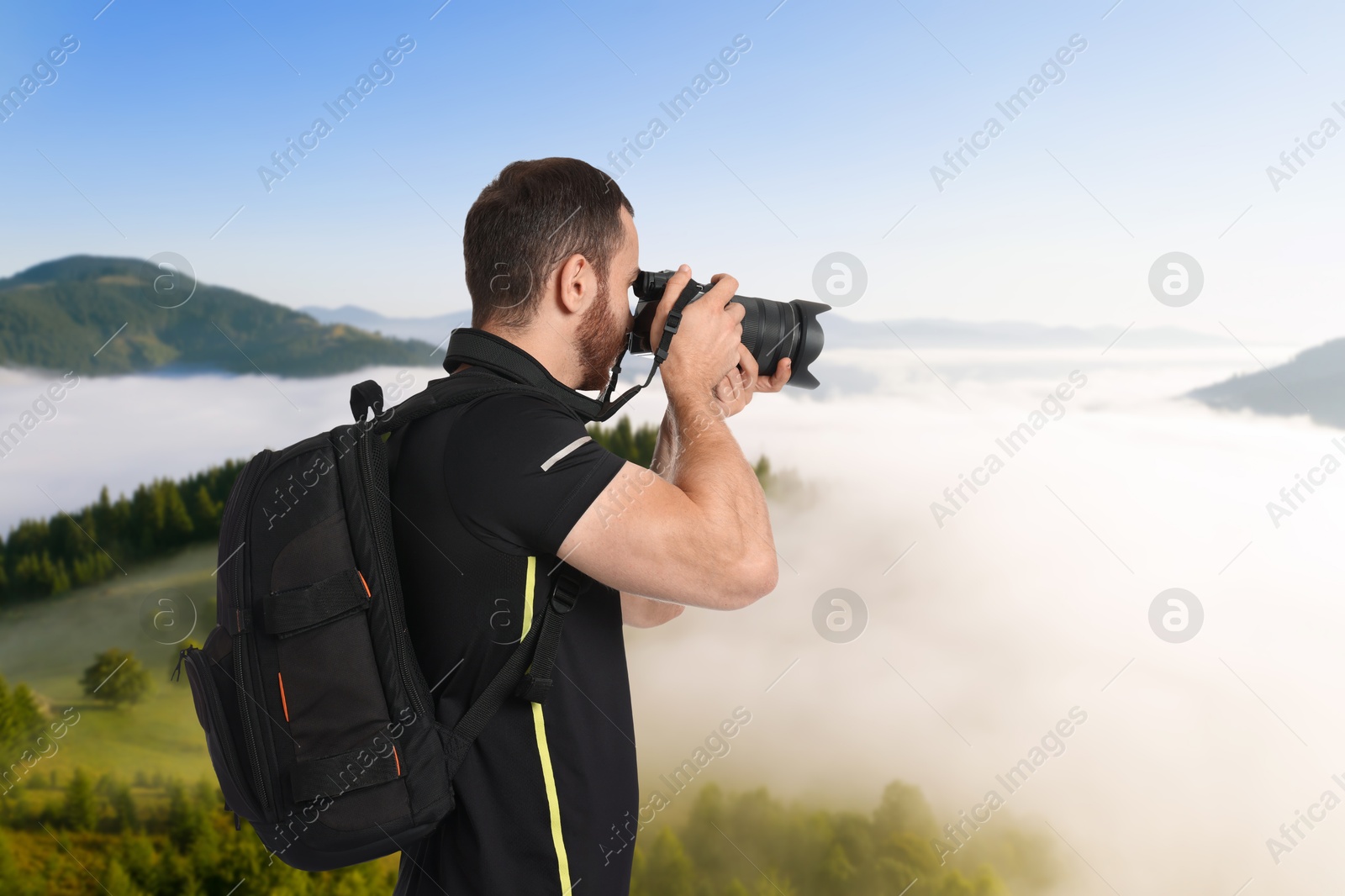 Image of Man with backpack taking photo in mountains