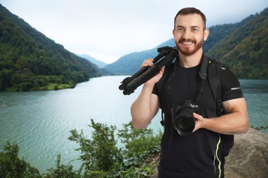 Image of Man with backpack and photography equipment near river in mountains