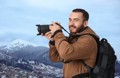 Image of Man with backpack taking photo in mountains