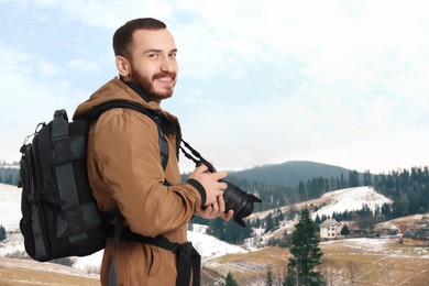 Image of Photographer with camera and backpack in mountains