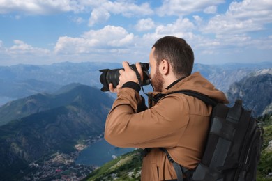 Image of Man with backpack taking photo in mountains