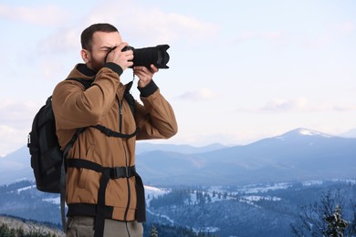 Image of Man with backpack taking photo in mountains