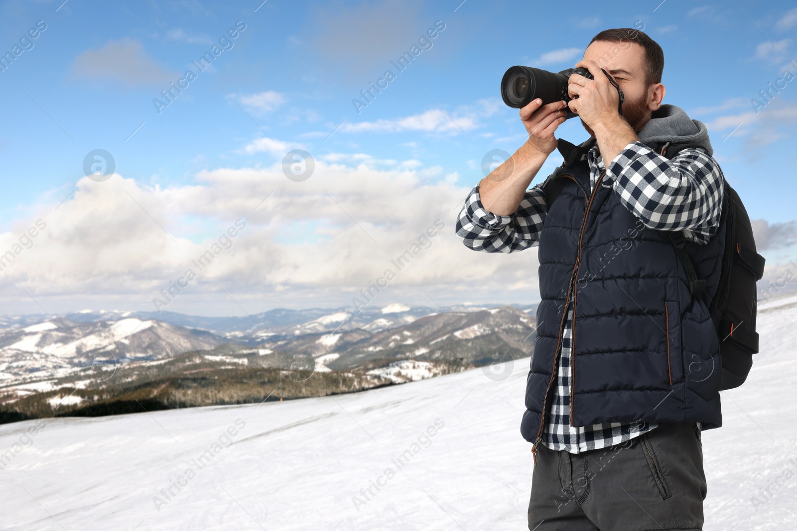 Image of Man with backpack taking photo in mountains