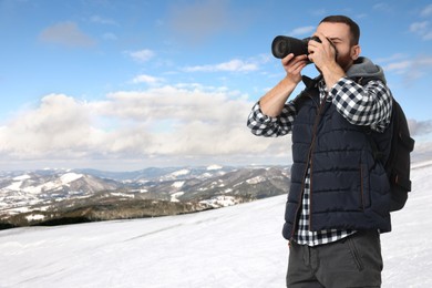 Image of Man with backpack taking photo in mountains