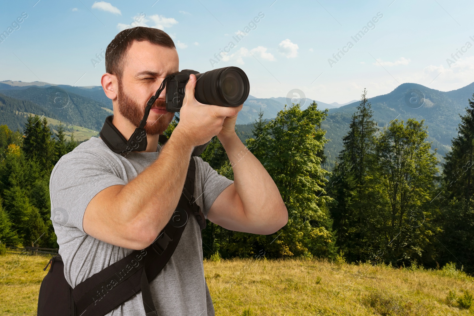 Image of Man with backpack taking photo in mountains