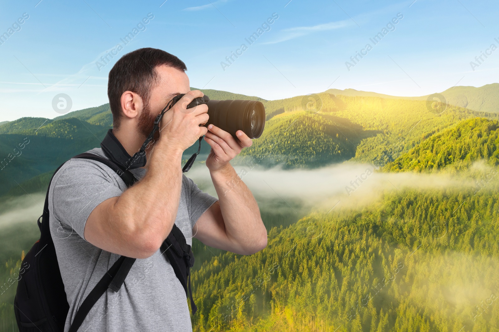 Image of Man with backpack taking photo in mountains