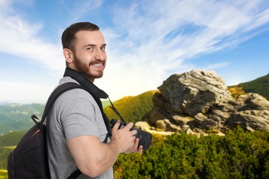 Photographer with camera and backpack in mountains