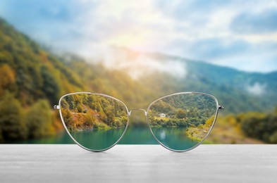 Image of Glasses against beautiful landscape. View through lenses more clear. Vision correction