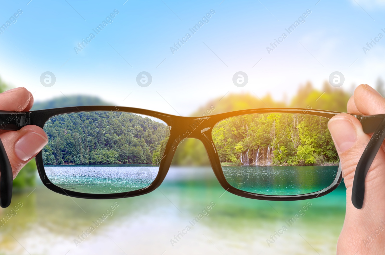 Image of Woman holding glasses against beautiful landscape, closeup. View through lenses more clear. Vision correction