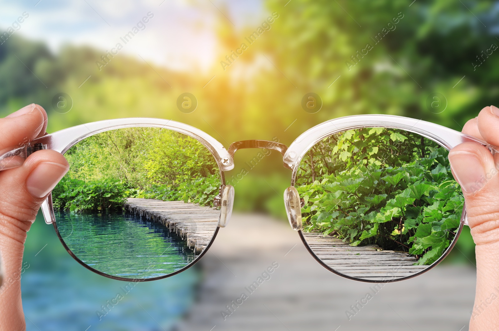 Image of Woman holding glasses against beautiful landscape, closeup. View through lenses more clear. Vision correction