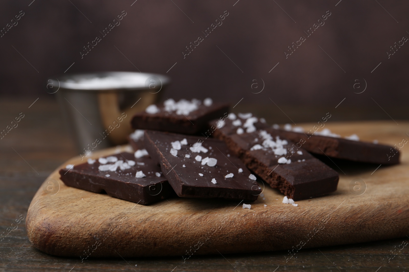 Photo of Pieces of chocolate with salt on wooden table, closeup