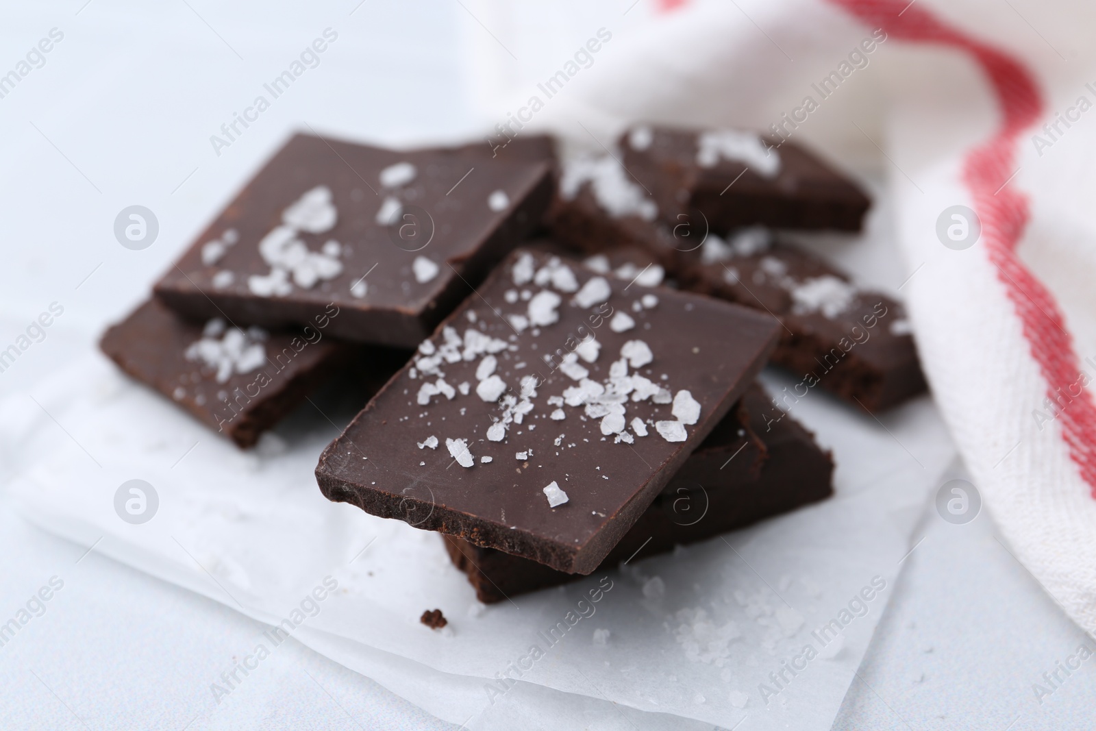 Photo of Pieces of chocolate with salt on white table, closeup