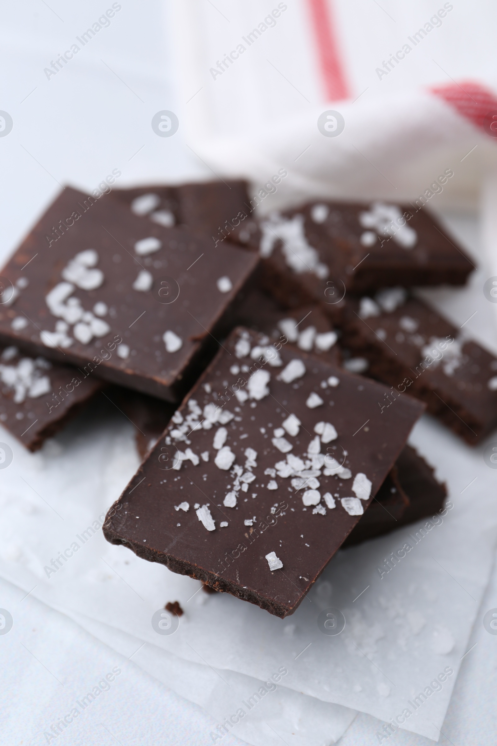 Photo of Pieces of chocolate with salt on white table, closeup