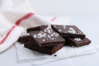 Photo of Pieces of chocolate with salt on white table, closeup