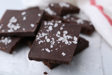 Photo of Pieces of chocolate with salt on white table, closeup