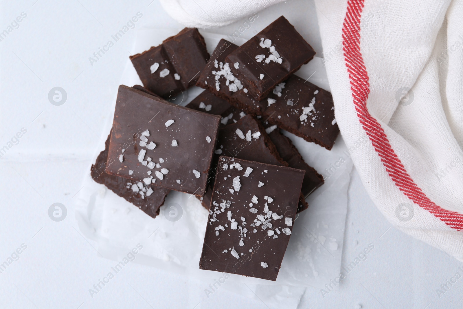 Photo of Pieces of chocolate with salt on white table, top view