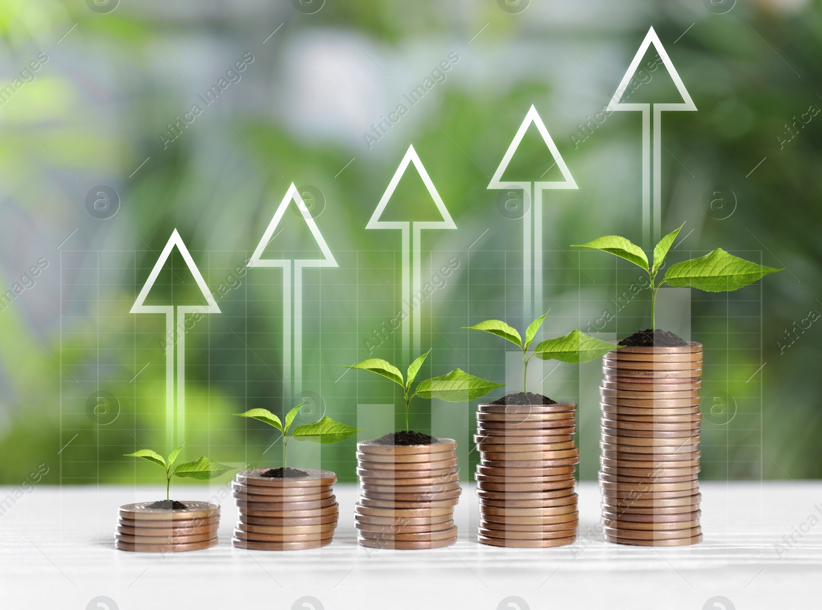 Image of Investment. Stacked coins with seedlings on tops and arrows against blurred background